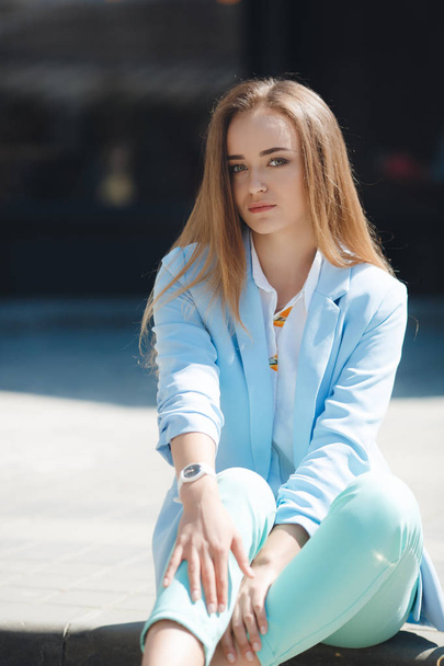 Portrait of a girl in a blue suit,sitting near the office - Photo, Image
