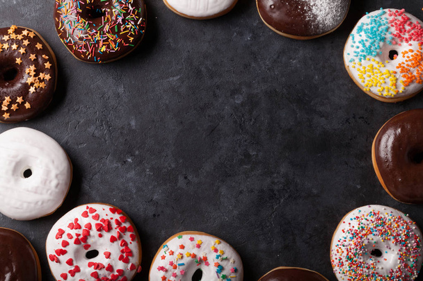 Colorful donuts on stone table - Φωτογραφία, εικόνα