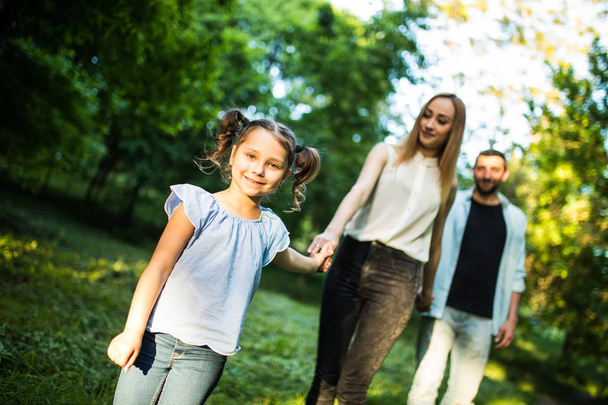 happy mother, father and little girl walking in summer park and having fun - Photo, Image