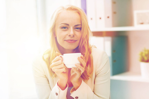 happy businesswoman drinking coffee at office - Foto, immagini