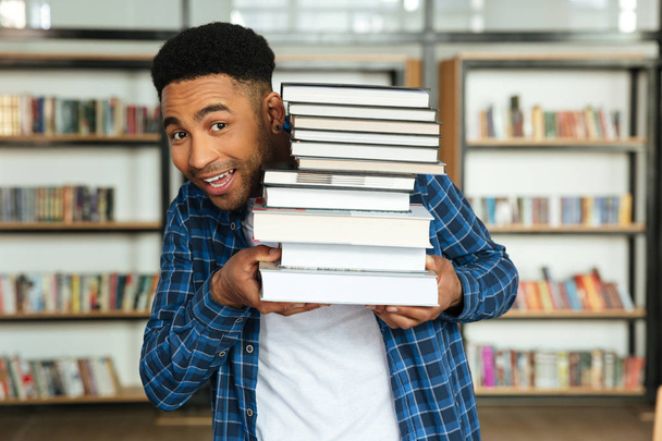 Jeune afro-américain mâle étudiant tenant pile de livres
 - Photo, image