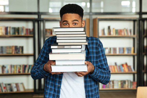 Joven afroamericano estudiante masculino sosteniendo pila de libros
 - Foto, Imagen