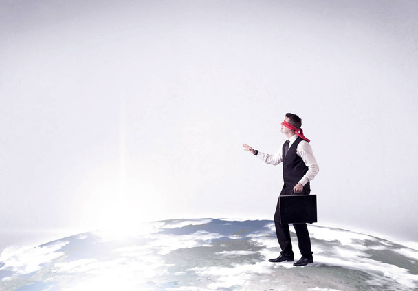 Blindfolded businessman steps on a realistic globe - Fotó, kép