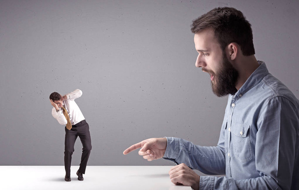 Young businessman fighting with miniature businessman - Foto, Imagen