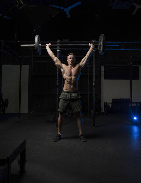 Muscular White Caucasian man does a barbell overhead press - Photo, image
