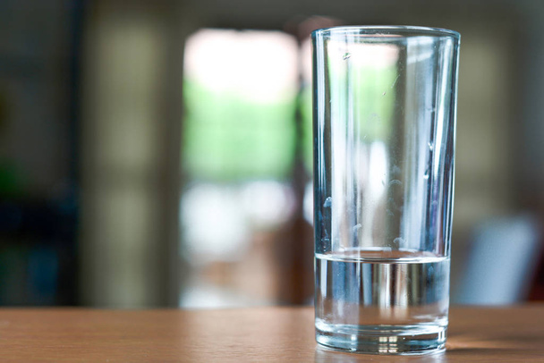 Склянка води на дерев'яному столі і фоні вітальні
 - Фото, зображення