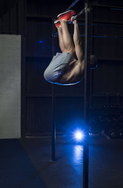 Muscular White Caucasian man doing foot to bar or leg lifts exercise - Fotoğraf, Görsel