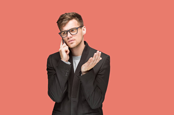The young caucasian businessman in glasses on red studio background talking on cell phone - Valokuva, kuva
