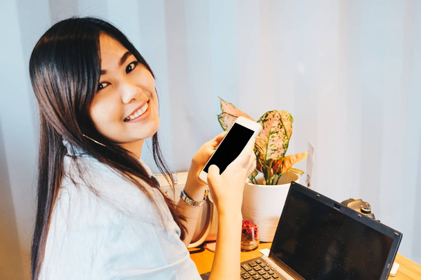 Femme assise dans un café à l'aide d'un ordinateur portable et d'un téléphone portable pour la recherche d'entreprise, entreprise de communication
 - Photo, image