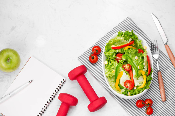 Frischer Salat, Hanteln und Notizblock - Foto, Bild