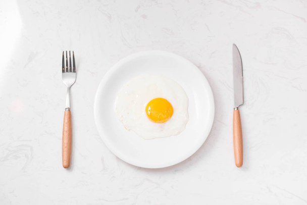 gebakken ei op plaat, vork en mes - Foto, afbeelding