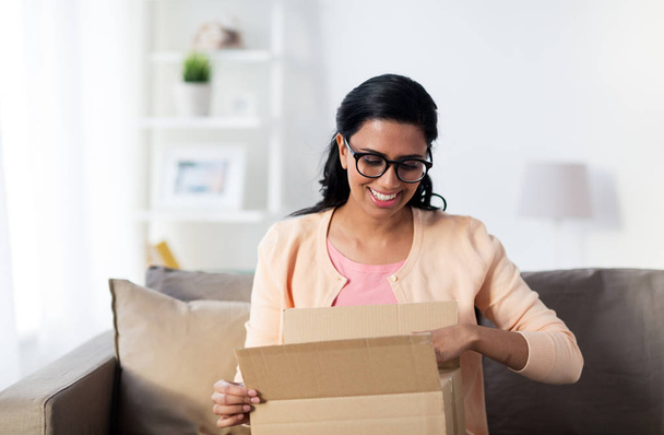 happy young indian woman with parcel box at home - Foto, afbeelding