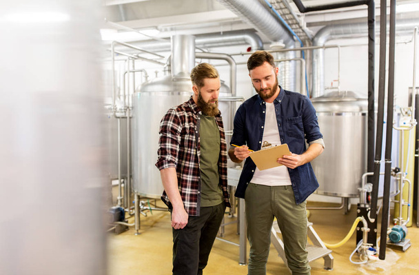 men with clipboard at craft brewery or beer plant - Фото, изображение