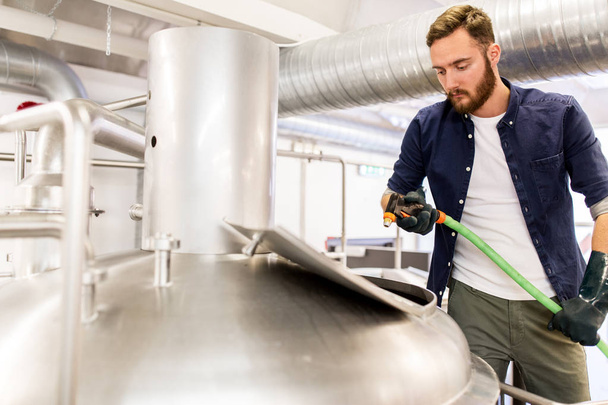 man with hose working at craft beer brewery kettle - Φωτογραφία, εικόνα