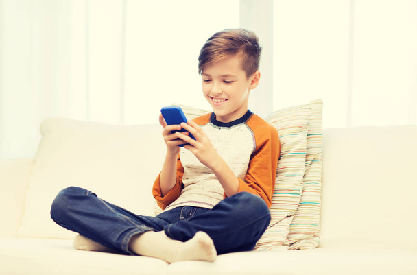 boy with smartphone texting or playing at home - 写真・画像