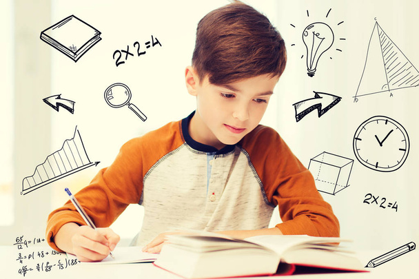 student boy with book writing to notebook at home - Foto, imagen