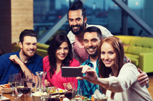 friends taking selfie by smartphone at restaurant - 写真・画像