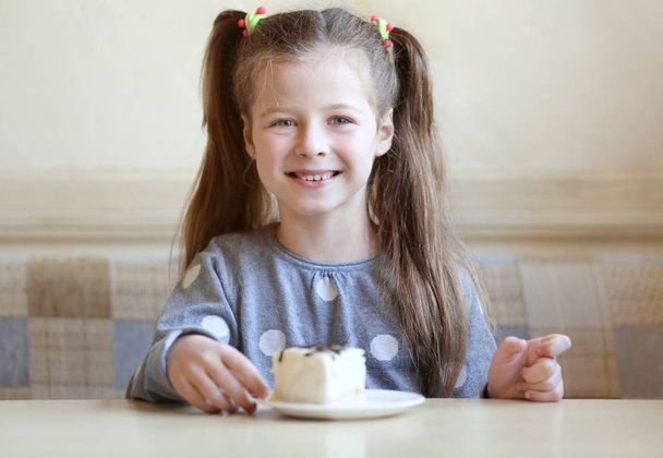 girl eating tasty cake in kitchen - Фото, изображение