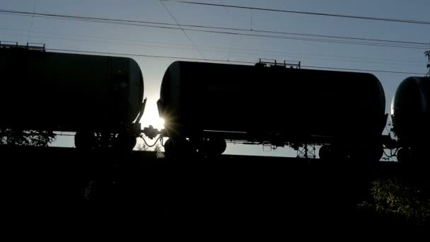 silueta de un tren de mercancías en movimiento con tanques contra el sol brillante
 - Metraje, vídeo
