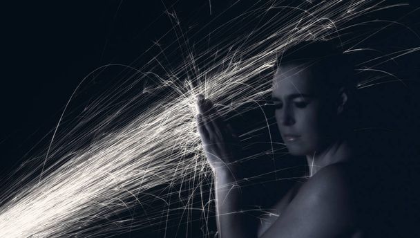 Long exposure photo of woman blocking glowing sparks artistic co - Foto, imagen