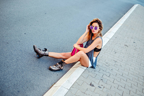 Модная девушка сидит на тротуаре
 - Фото, изображение
