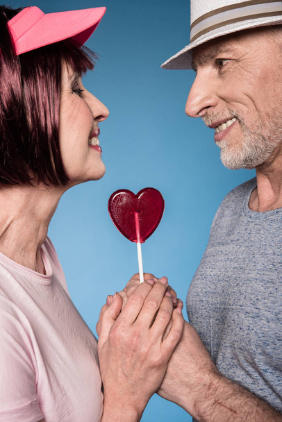 elderly couple holding hands with lollipop - Photo, Image