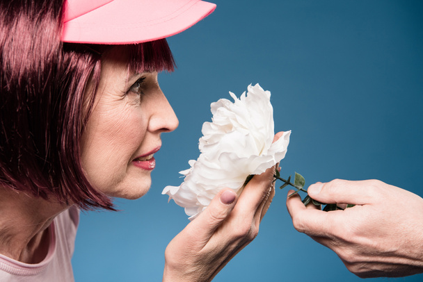 bela mulher idosa cheirando flor
 - Foto, Imagem