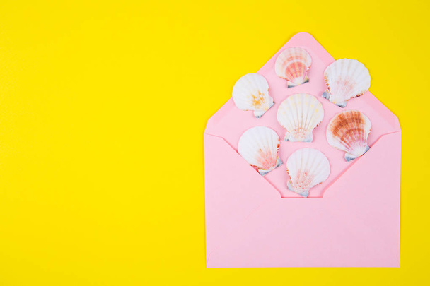 ピンクの封筒色黄色 backgro で多くの貝殻 - 写真・画像