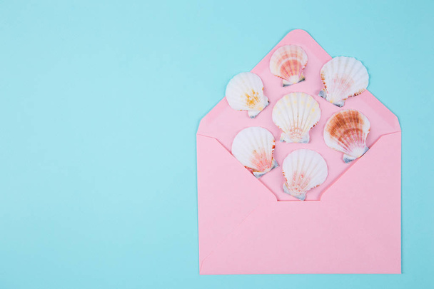 ピンクの封筒色ミント青バックに多くの貝殻 - 写真・画像