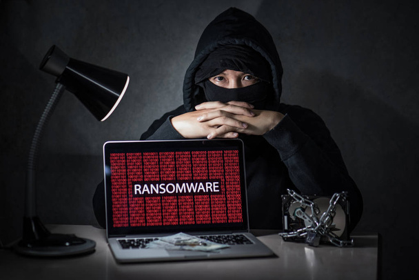 Hacker with computer screen showing ransomware attacking - Photo, Image