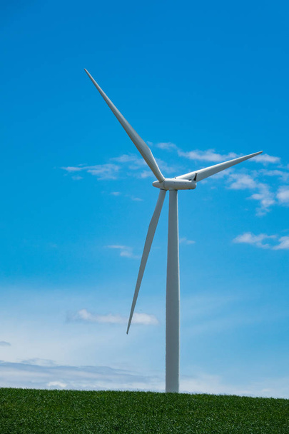 Single white wind turbine rising in a blue sky - Фото, изображение