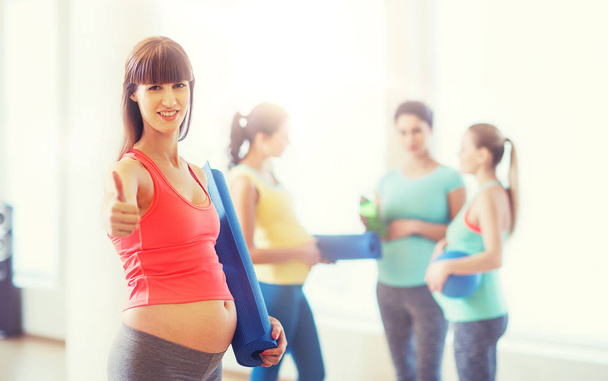 pregnant woman with mat showing thumbs up in gym - Fotoğraf, Görsel