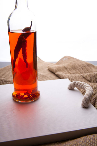 Een fles wodka en rode chilipepers - Foto, afbeelding