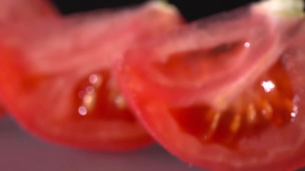 Primer plano de tomates frescos en rodajas sobre el fondo negro cámara lenta
 - Metraje, vídeo