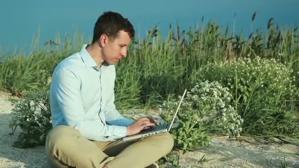 Az ember ül a strandon, egy laptop. Szabadúszó - Felvétel, videó