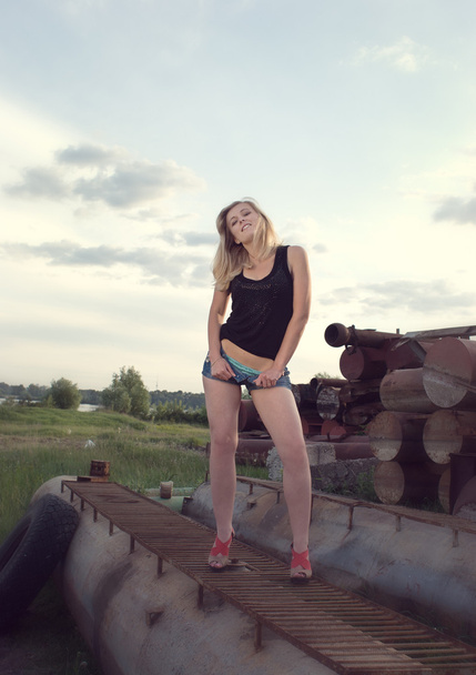 Stylish portrait of young girl posing over industrial background - Zdjęcie, obraz