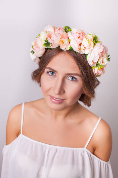 Portrait of a beautiful girl with flowers on her head on a white background. - 写真・画像