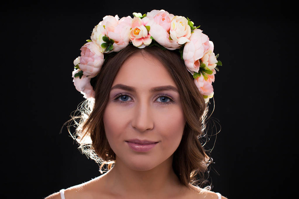 Beautiful girl with flowers on her head on a black background - 写真・画像