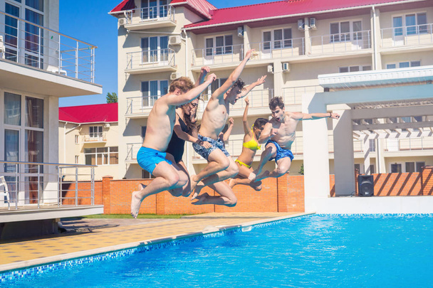 Fiesta en la piscina. Grupo de amigos alegres saltando al agua
. - Foto, Imagen