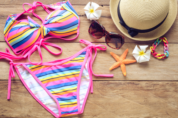 Beauté bikini coloré et accessoires sur le sol en bois pour le voyage
  - Photo, image