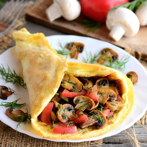 Vegetarian omelette idea. Fried mushrooms omelette with tomatoes and dill on a plate. Fresh mushrooms, tomatoes, dill on a vintage wooden background. Easy egg omelette. Rustic style. Healthy food - Photo, Image