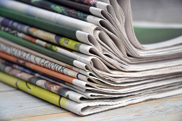 Stacked and piled up newspapers on a wooden table background - Photo, Image