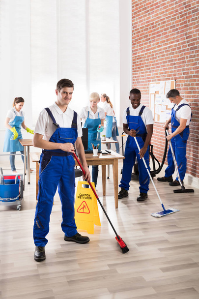 Group Of Diverse Janitors In Uniform Cleaning The Office With Cleaning Equipments - 写真・画像