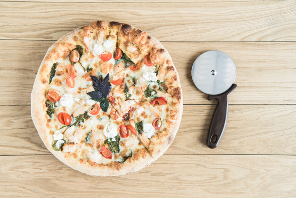 italian pizza with cutter on wooden tabletop - Φωτογραφία, εικόνα