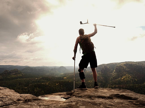 Happy man hiker  holding medicine crutch above head,  injured knee fixed in  knee brace feature.  - Photo, Image