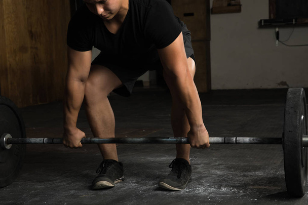 Sportos férfi egy súlyzó emelésére az edzőteremben - Fotó, kép