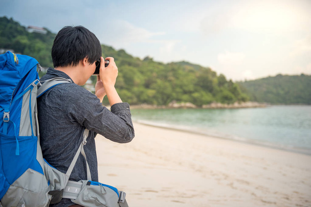 Jonge Aziatische backpacker fotograferen op het strand - Foto, afbeelding