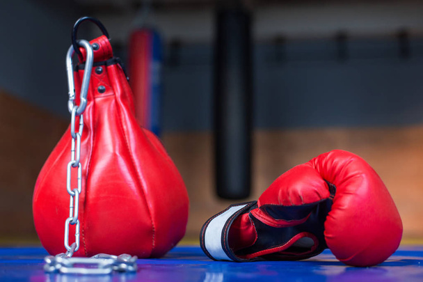 A small red punching bag with a chain next to the boxing glove - Photo, Image