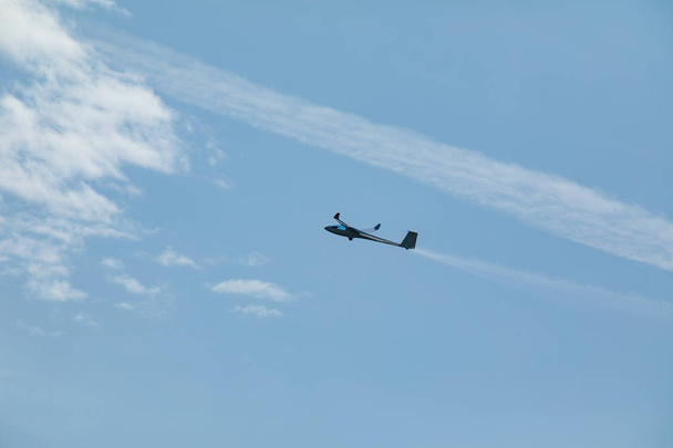 Глайдер, летящий в голубом небе, выбрасывает воду перед посадкой.
. - Фото, изображение