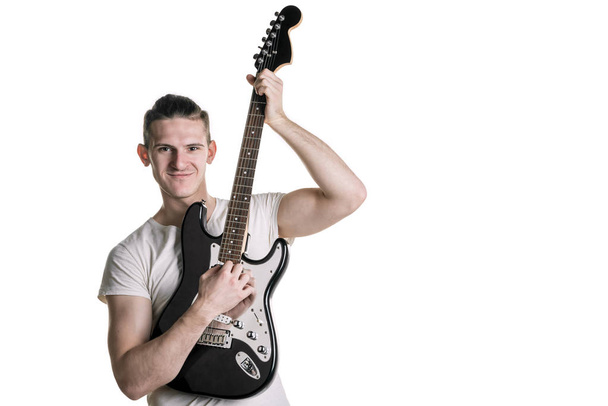 Hudba a kreativity. Pohledný mladý muž v tričku hraje elektrickou kytaru. Vodorovný rámeček - Fotografie, Obrázek